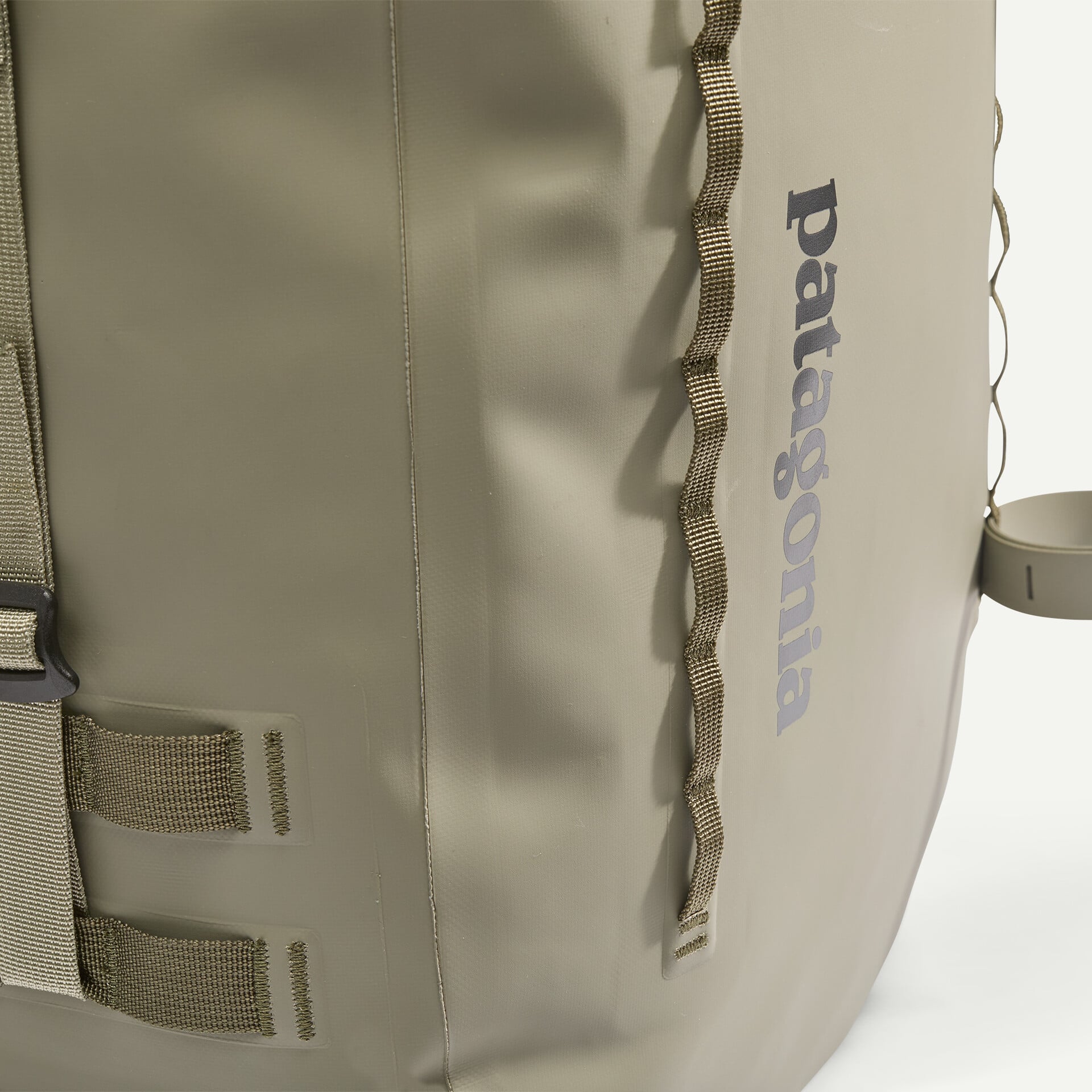Olive Patagonia Guidewater roll-top pack close-up showing smooth waterproof body, daisy-chain webbing and vertical logo