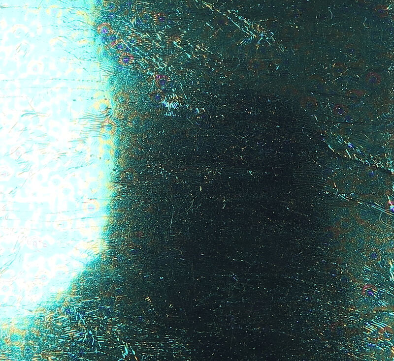 Iridescent teal-green Sili Skin silicone sheet with holographic scratched texture and dark center for fly tying