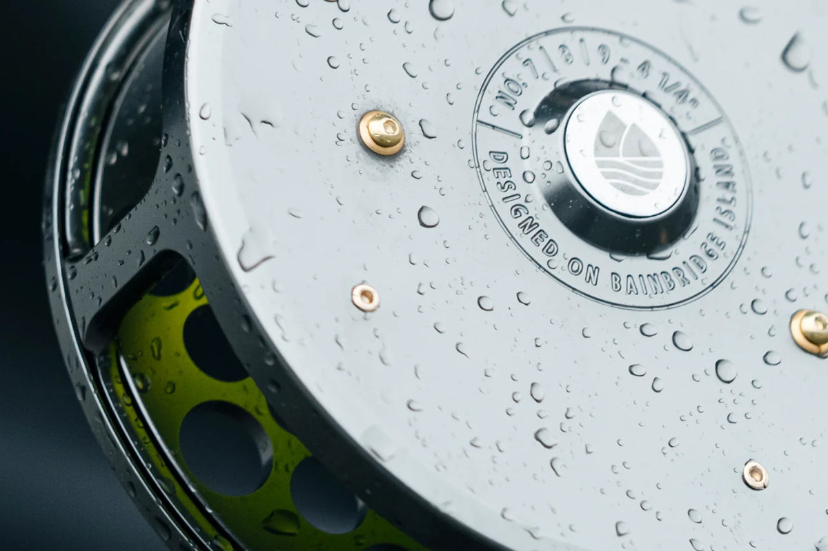 Silver Redington Classic Spey fly reel with water droplets, anodized lime-green perforated spool and brass rivets