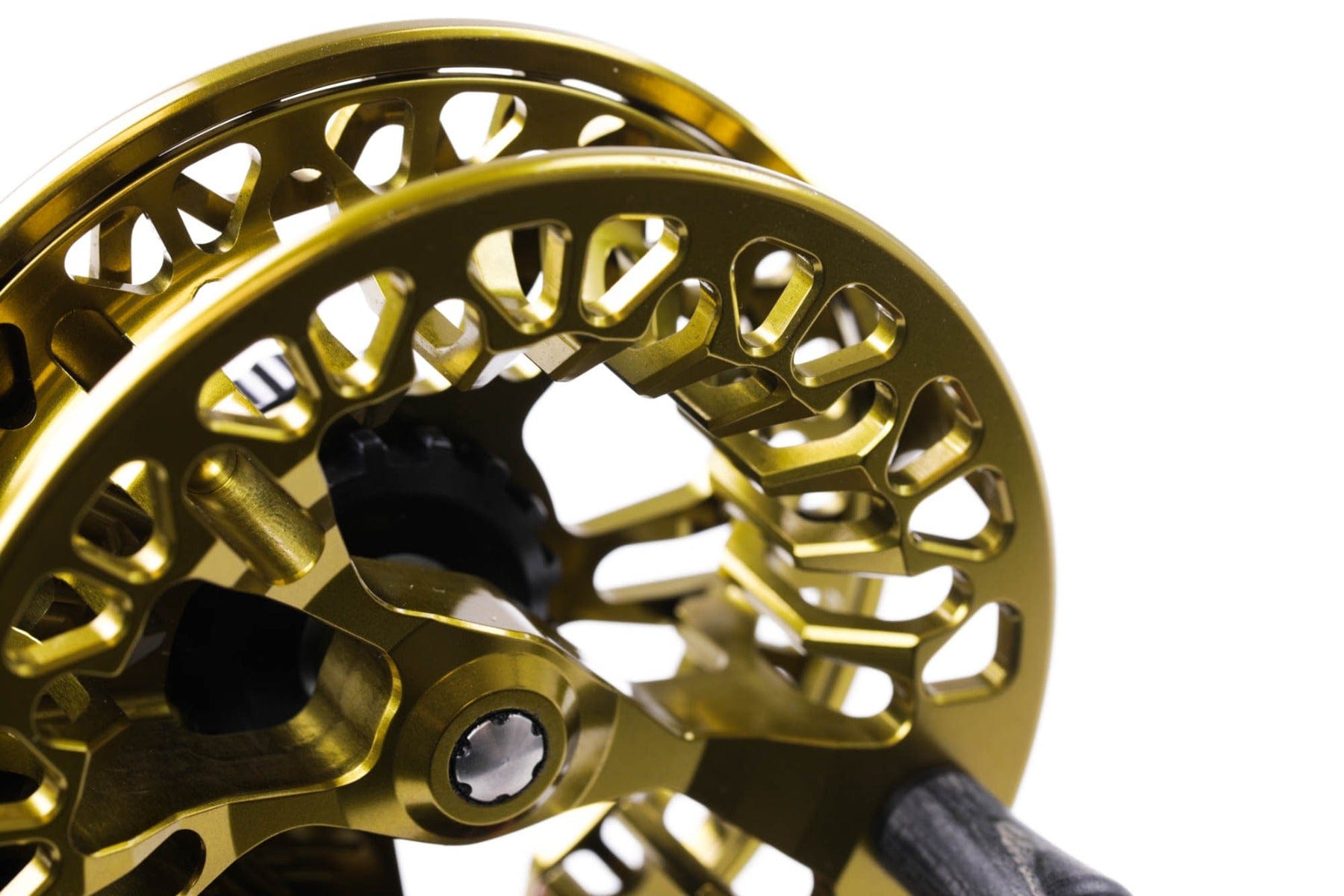 Close up gold anodized Abel VAYA fly reel with CNC-machined porting, open spool design and black drag knob