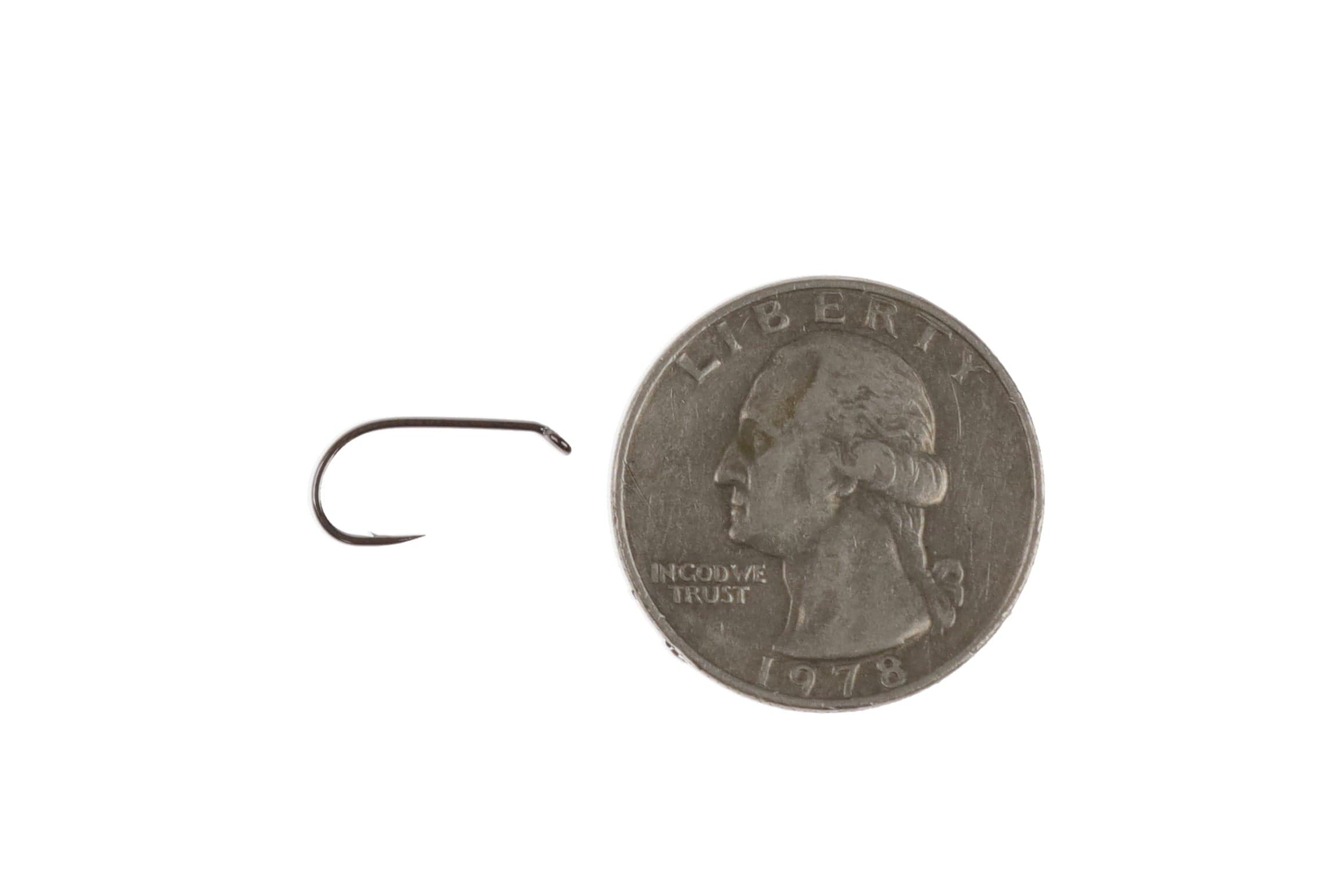 Ahrex FW504 short-shank dry fly hook, dark bronze steel with curved eye, shown beside a US quarter for scale