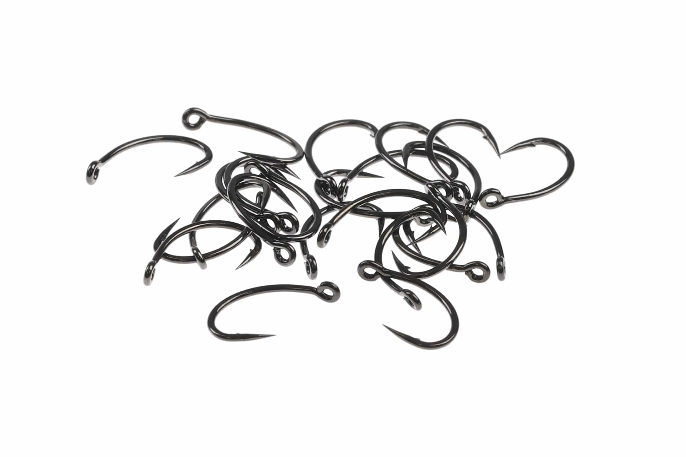 Glossy black Ahrex FW524 Super Dry fly tying hooks with curved shanks and sharp points scattered on white background