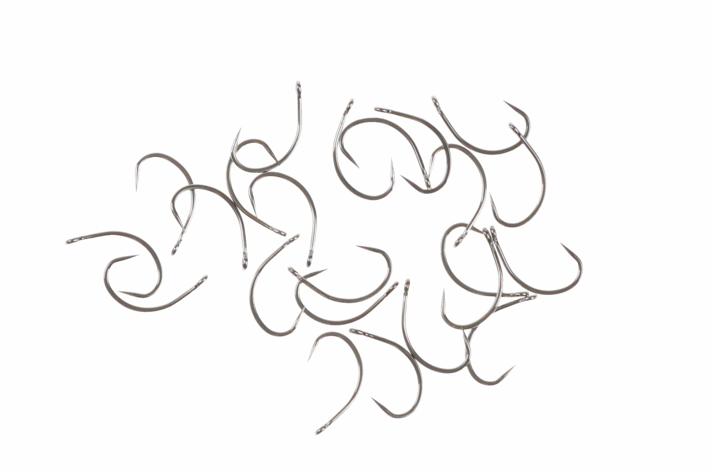 Scattered silver Ahrex FW525 barbless hooks for fly tying, curved shanks and straight eyes on white background