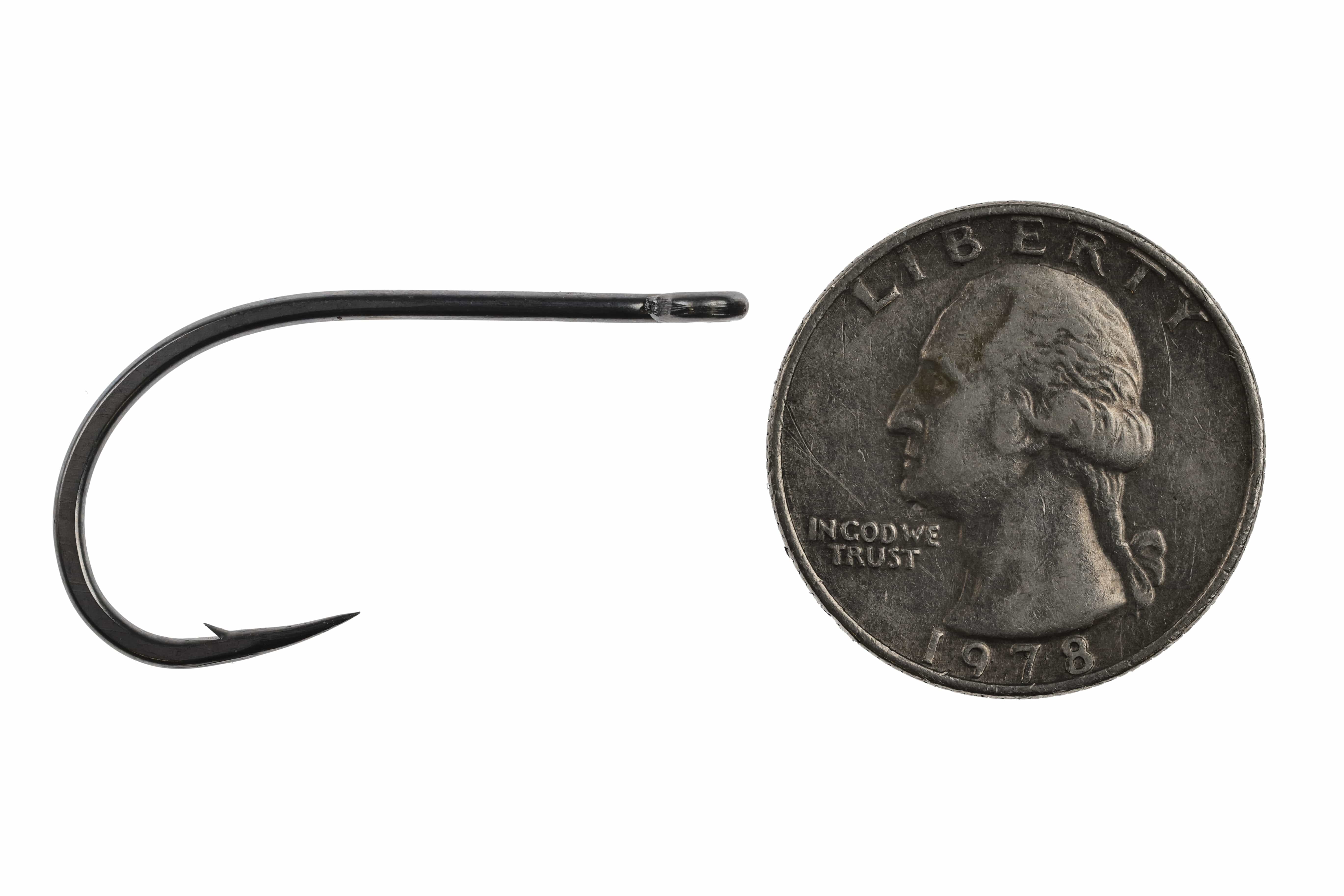 Black Ahrex SA270 Bluewater fly-tying hook with curved steel shank and barb beside US quarter for scale