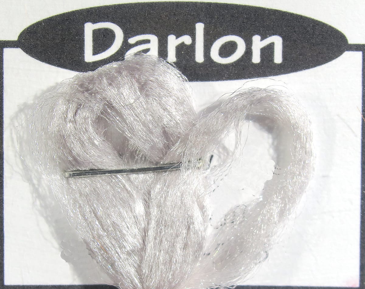 Silver-white Darlon synthetic fiber bundle for fly tying, shiny translucent strands stapled to white card