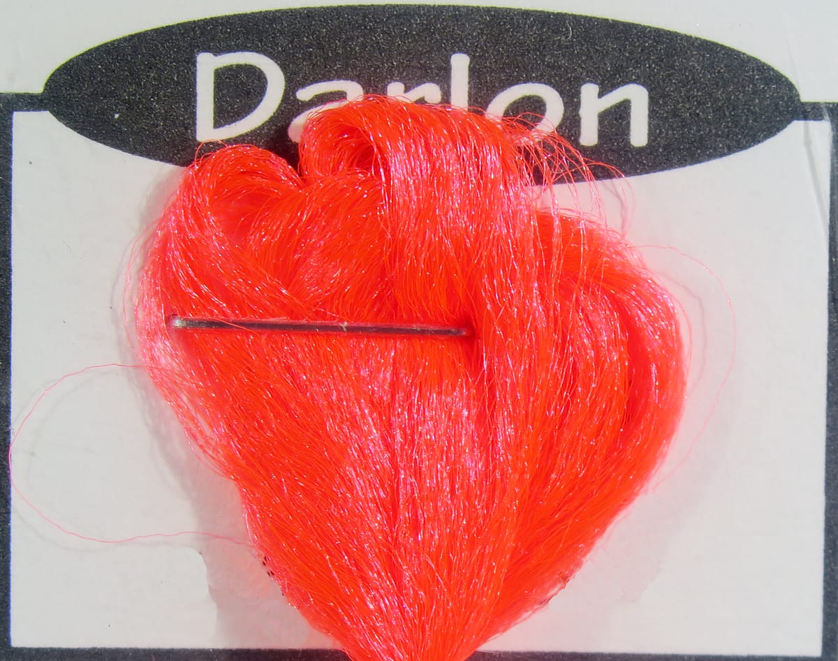 Bright fluorescent orange Darlon synthetic fibers looped and pinned on card for fly tying