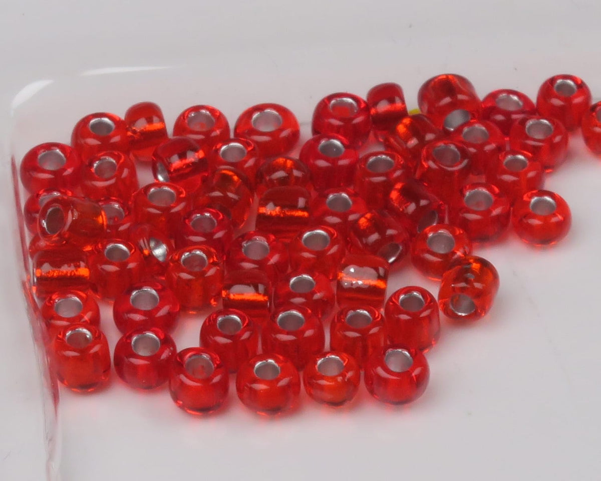 Red transparent glass fly-tying beads with silver-lined holes, scattered seed bead style