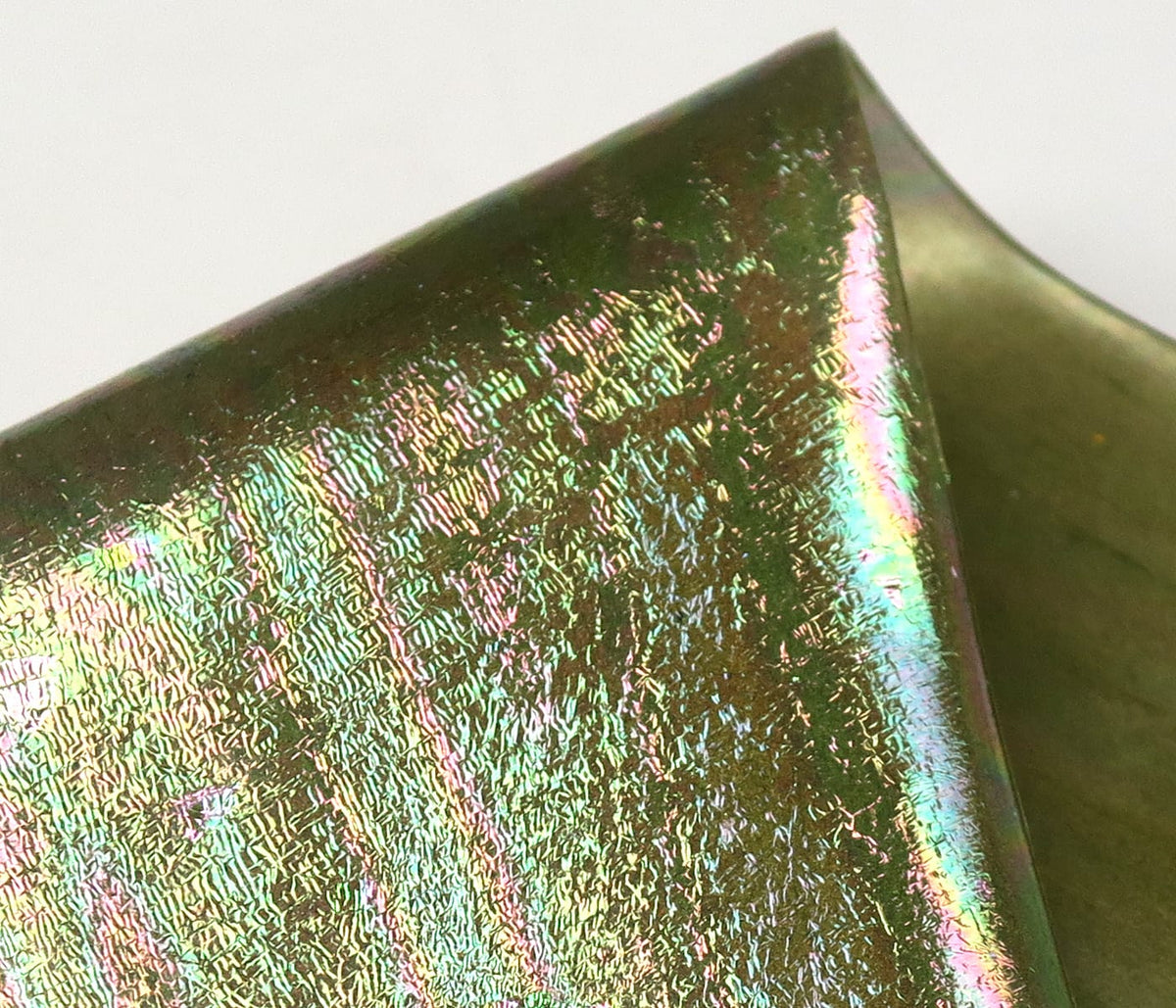 Close-up iridescent olive-green UV Chewee skin with holographic rainbow sheen and crinkled foil texture for fly tying