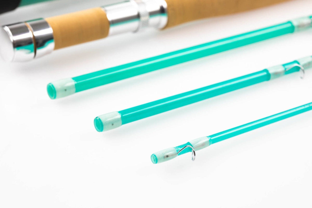 Turquoise glass fly rod sections with cork handle and polished silver reel seat, close-up on white background