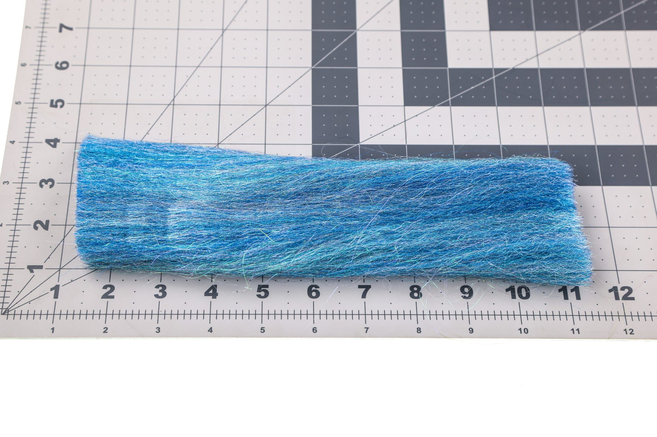 Bright blue iridescent synthetic fibers strip for fly tying, layered textured 3D sculpt-a-fly material on grid cutting mat