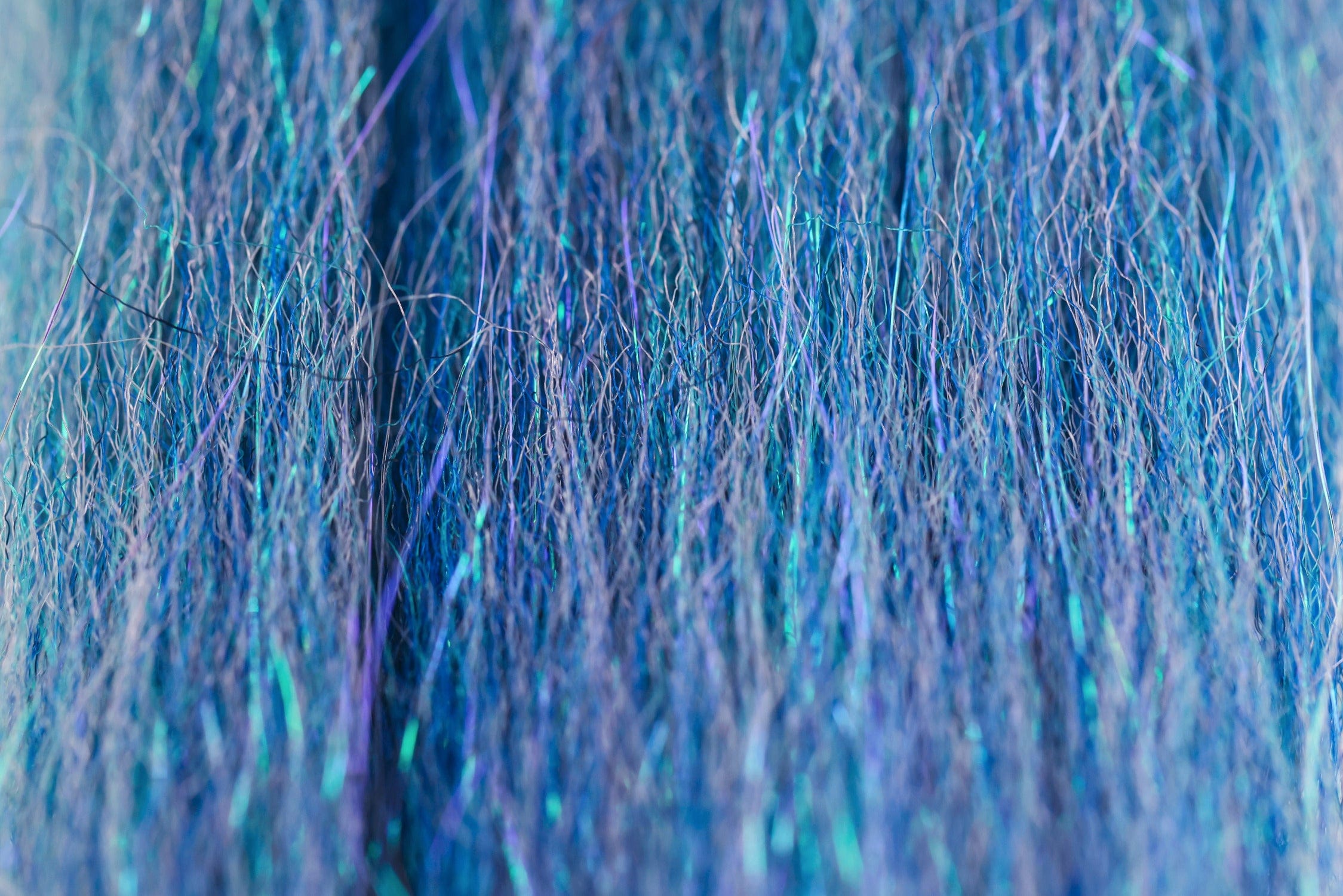 Iridescent blue and teal synthetic fly tying fibers with fine hairlike strands and reflective sparkle