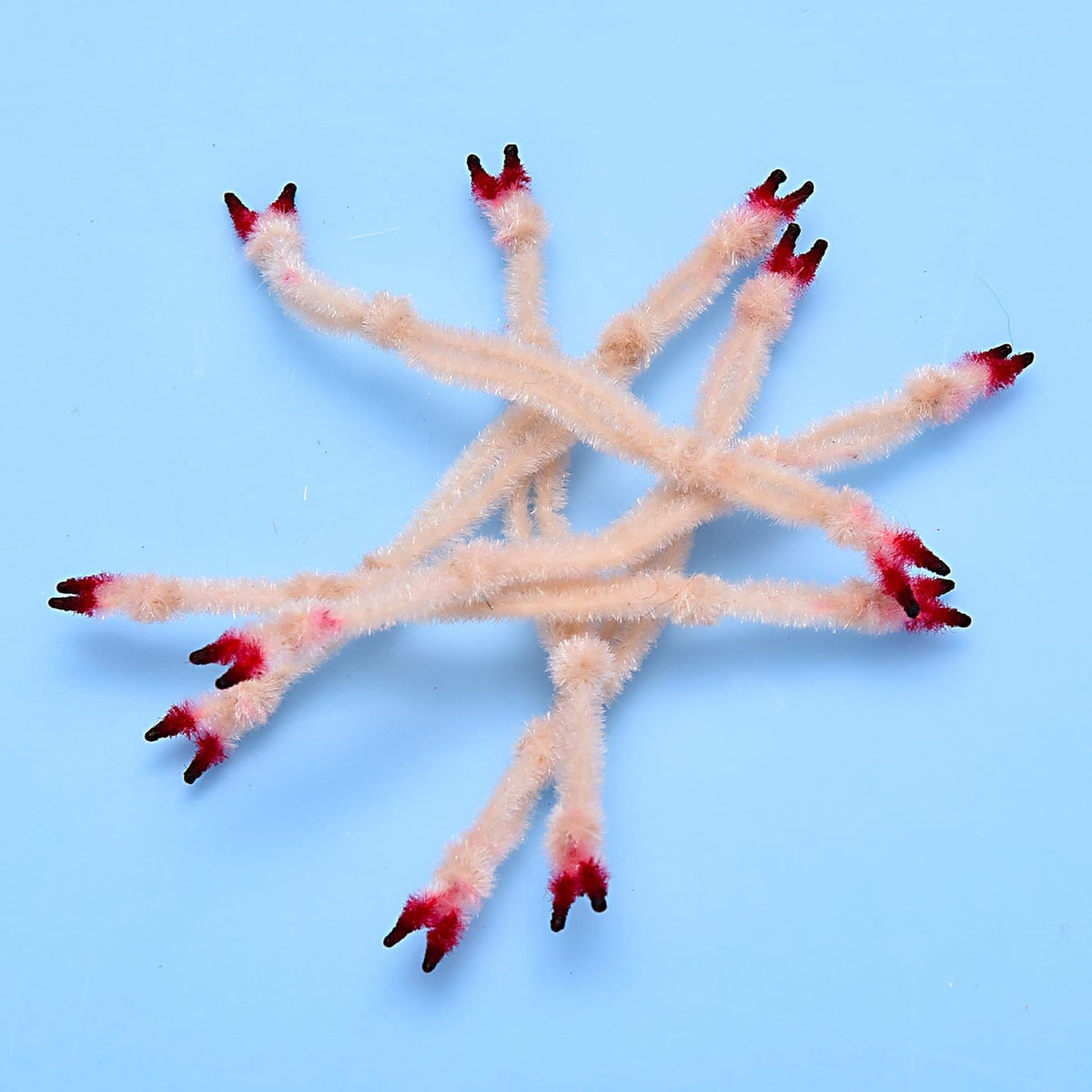 Peach fuzzy crab claws with red-black tipped ends for fly tying, plush segmented appendages on blue background