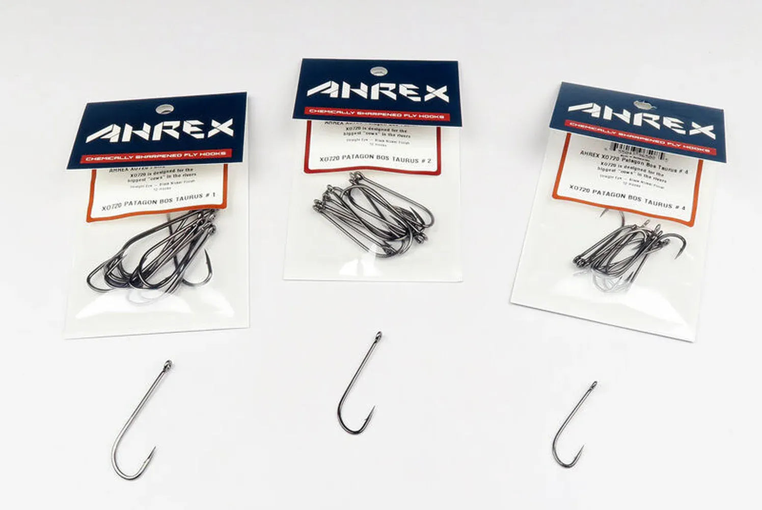 Ahrex Patagon Bos Taurus silver streamer hooks in clear packs with navy headers and three loose fly-tying hooks on white