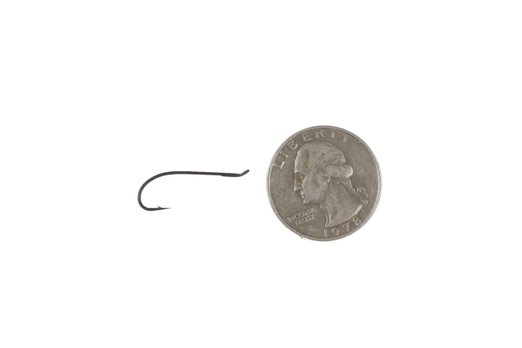 Matte black Ahrex HR413 single fly hook, slim curved steel shank with upturned point shown next to quarter for scale