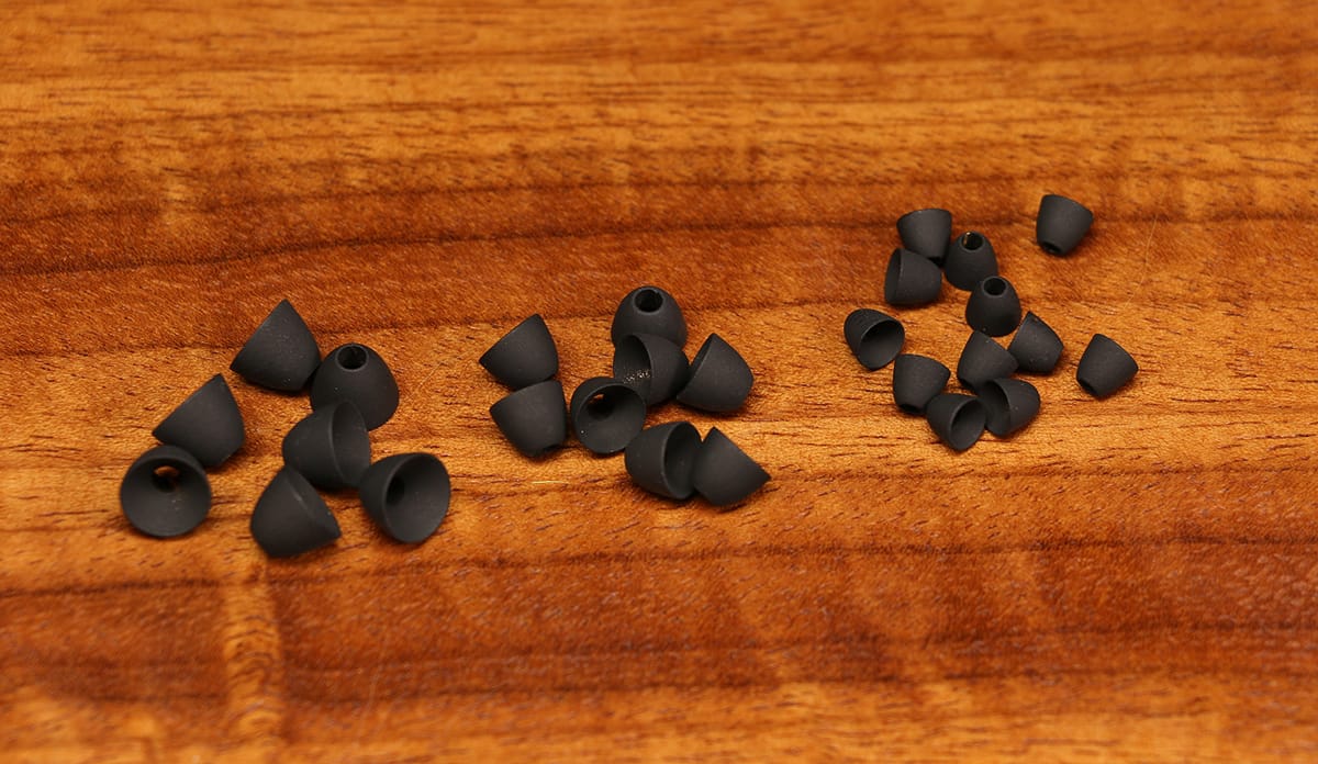 Hareline fly tying matte black cone heads, small hollow metal cones with center holes grouped on wooden surface