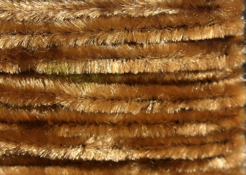 Golden brown chenille strands, plush shiny synthetic fibers with metallic sheen for fly tying