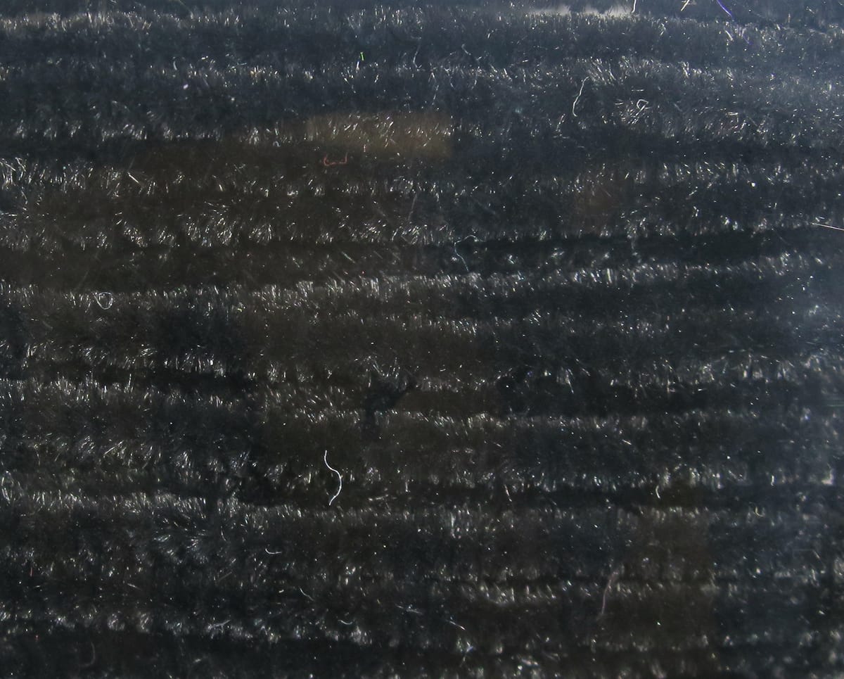 Black Hareline chenille with dense fuzzy fibers, subtle shimmer and ribbed texture for fly tying