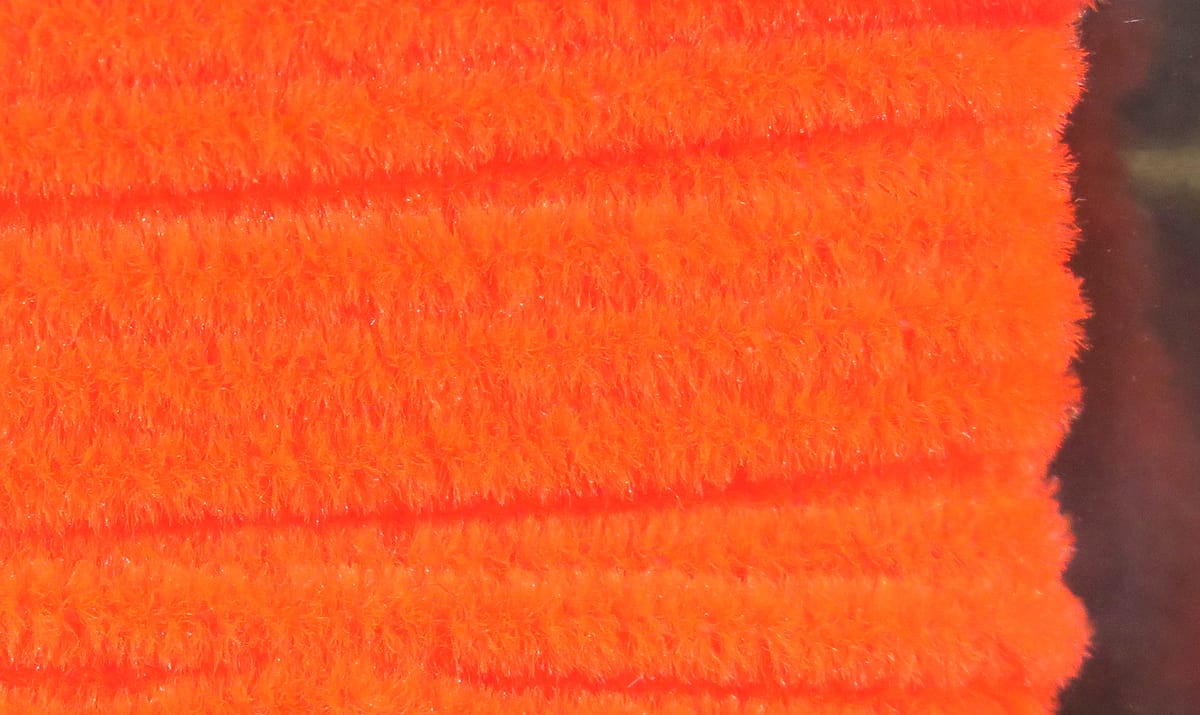 Bright fluorescent orange Hareline chenille with dense fuzzy synthetic fibers for fly tying