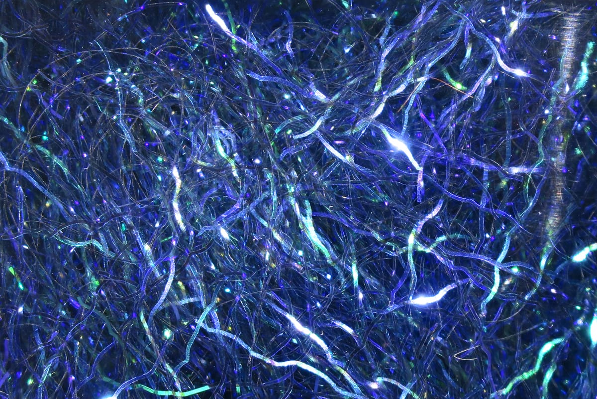 Iridescent blue-purple synthetic dubbing fibers with green shimmer, tangled reflective fly tying material