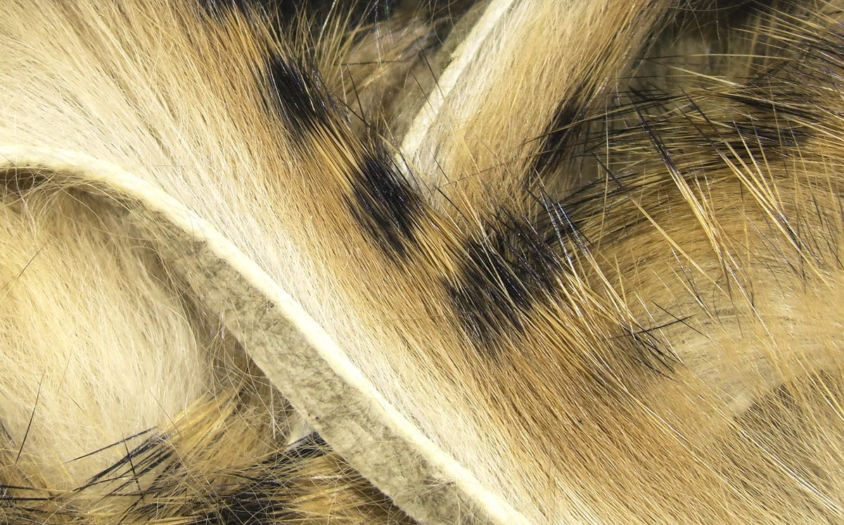 Micro pulsator strips close-up showing tan and cream fur with black-tipped guard hairs and felt backing for fly tying