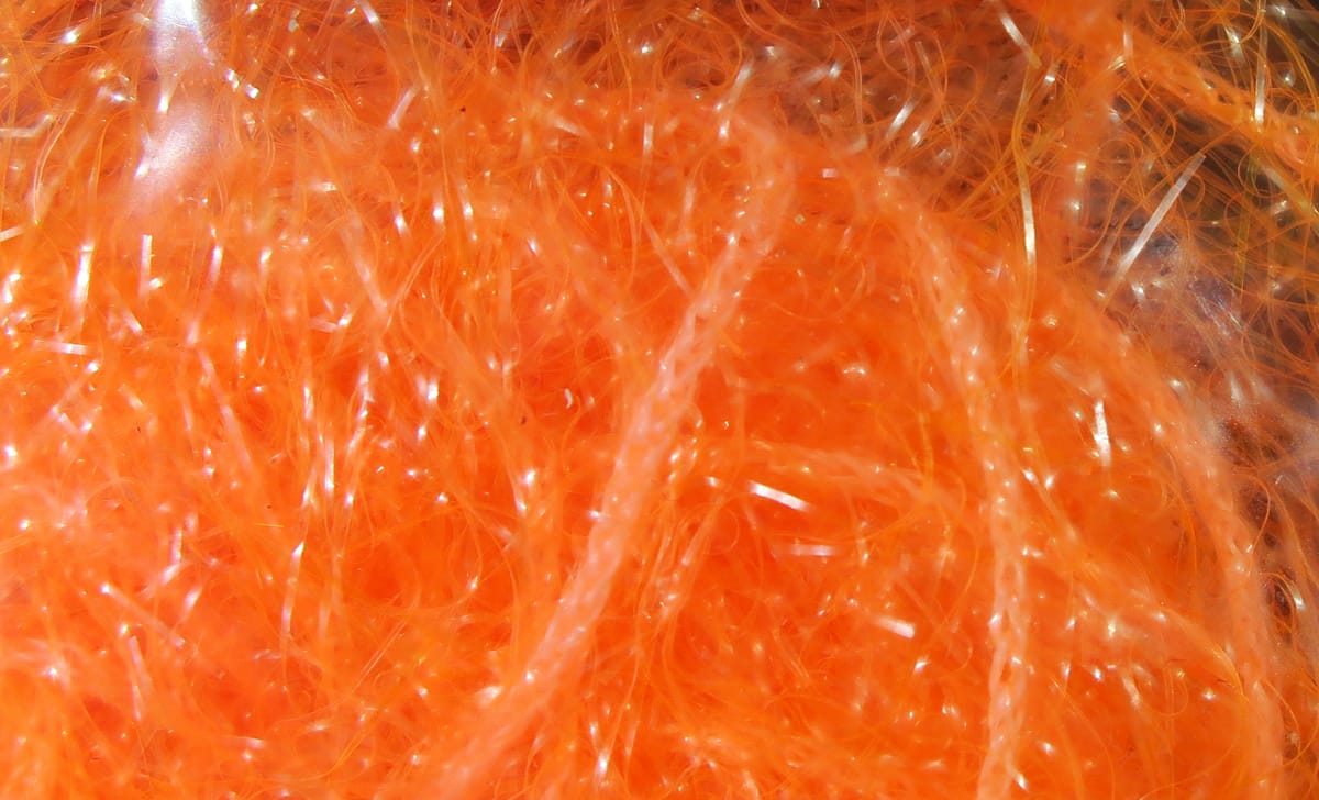 Bright orange Hareline Polar Chenille, fluffy synthetic fibers with iridescent tinsel for fly tying