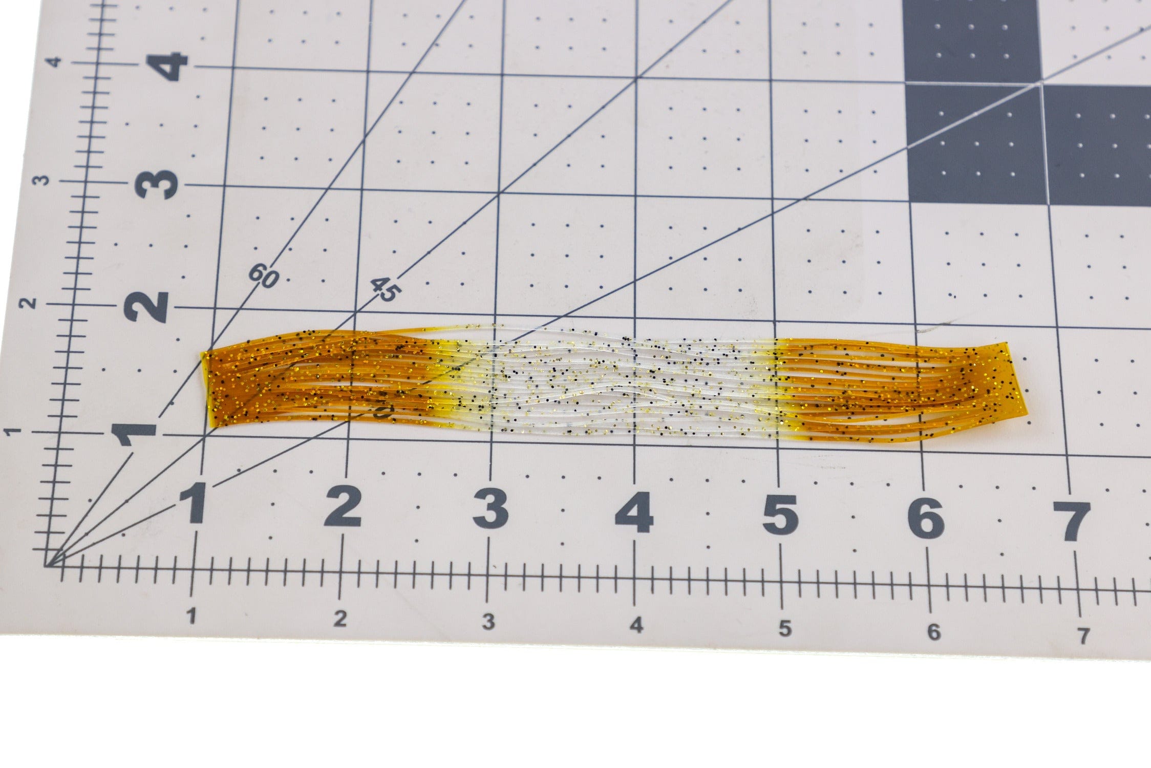 Amber-to-white translucent synthetic Shrimpy Crabby Legs strands with black and gold glitter for fly tying