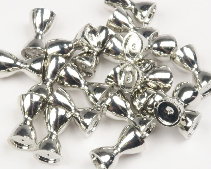 Silver-toned brass sunken barbell fly tying eyes, reflective double-cone beads piled on white background