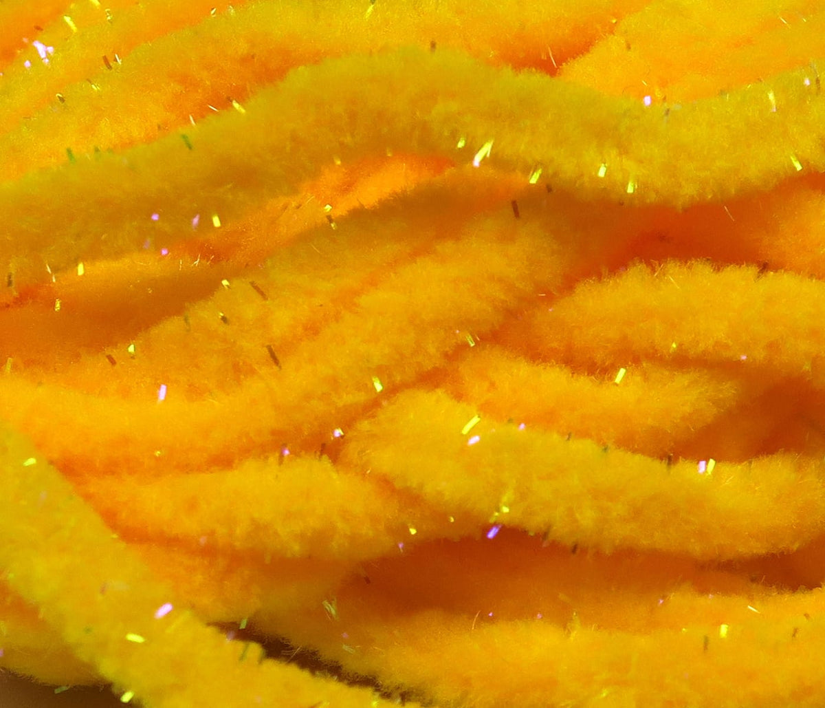 Fluorescent yellow-orange mop chenille strands with fuzzy texture and iridescent tinsel flecks for fly tying