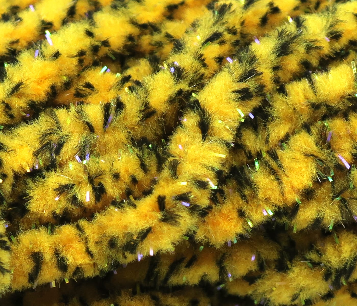 Yellow and black mottled mop chenille with fluffy texture and iridescent UV tinsel strands for fly tying