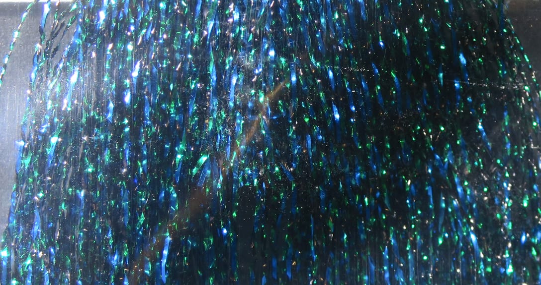 Hedron Flashabou weave: iridescent blue-green metallic tinsel strands woven for fly tying, shimmering reflective material