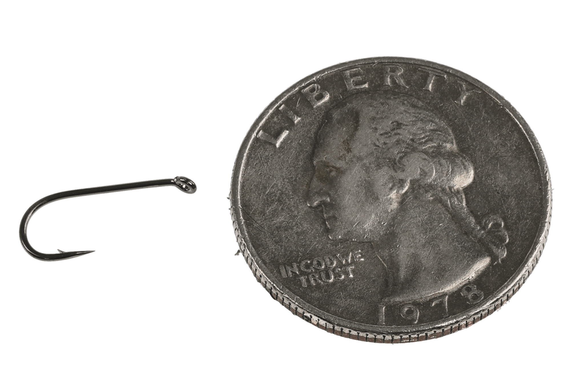 Kona dark metal universal dry fly hook with curved shank and small barb beside US dime for size, fly tying hook