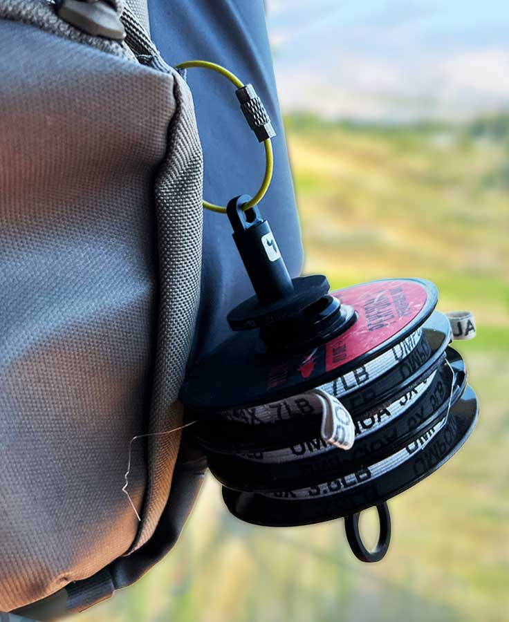 Loon Rogue Tippet Post black plastic spool holder with stacked tippet reels and olive locking wire attached to gray pack