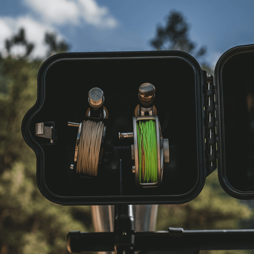 Black fishing rod quiver holding two spools of line with brown and green cord on outdoor vehicle mount