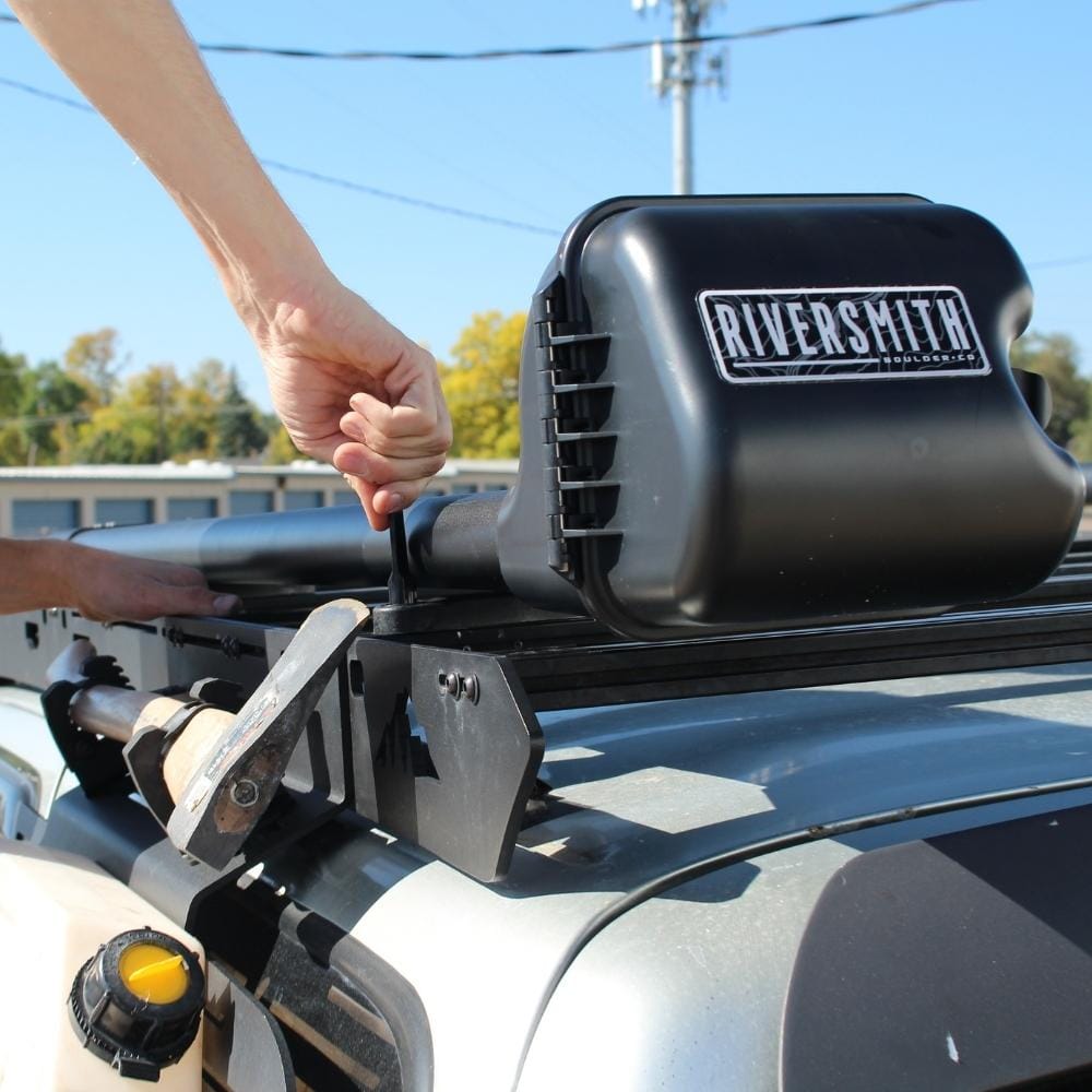 Riversmith black low-profile T-track mount rod rack accessory installed on truck bed rail with hand adjusting lever