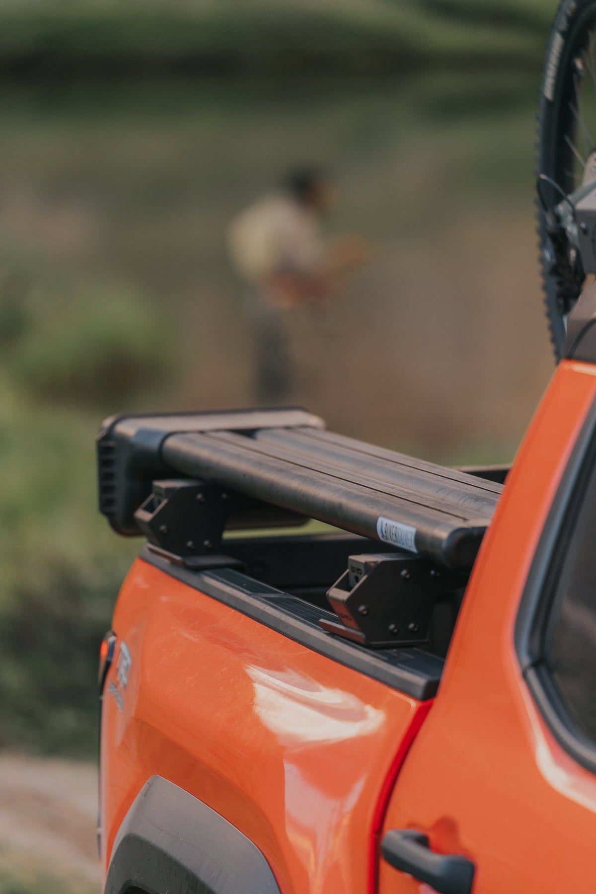 Riversmith ShortCut orange vehicle fishing rod rack mounted on truck window displaying black rod holders