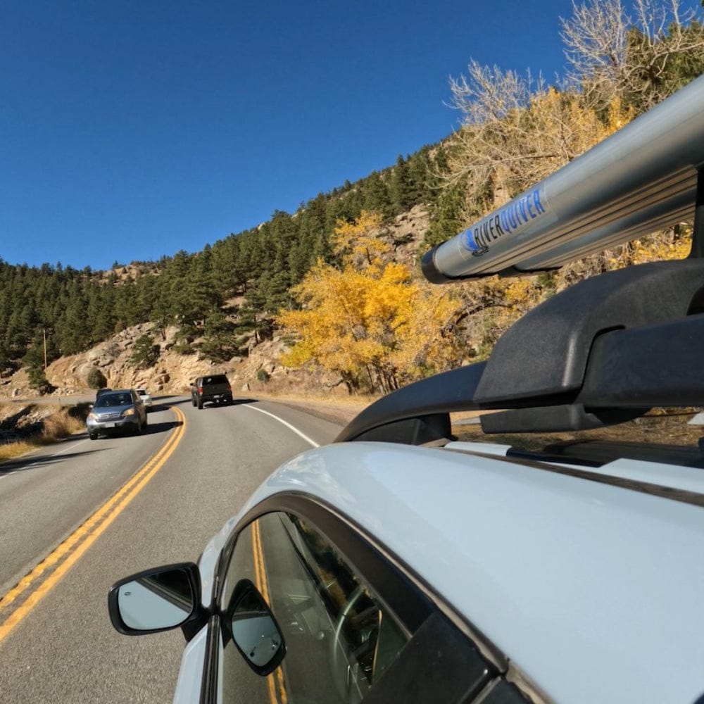 Riversmith ShortCut fishing rod rack mounted on white SUV roof during mountain drive