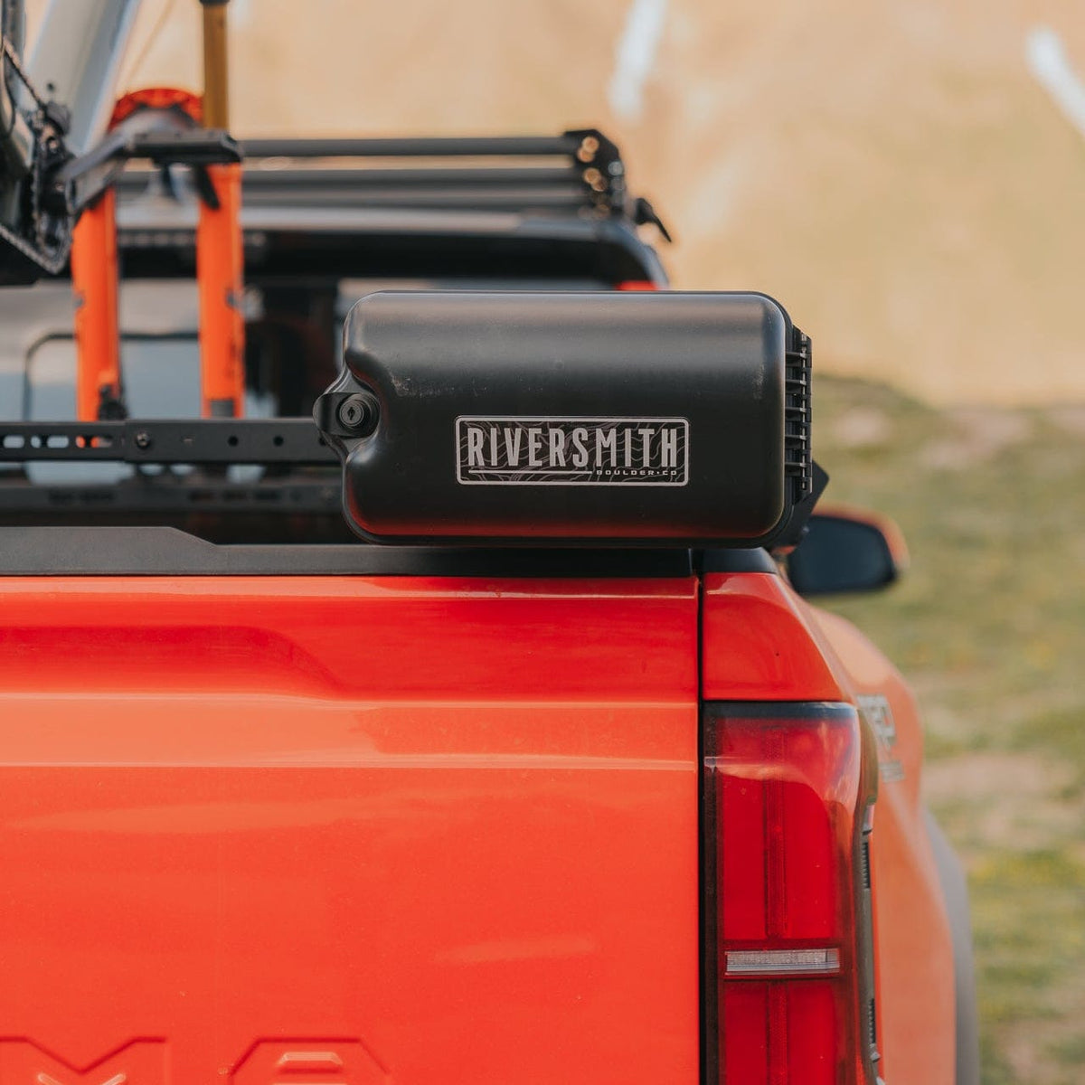 Riversmith ShortCut black fishing rod quiver mounted on red truck bed with orange roof rack system
