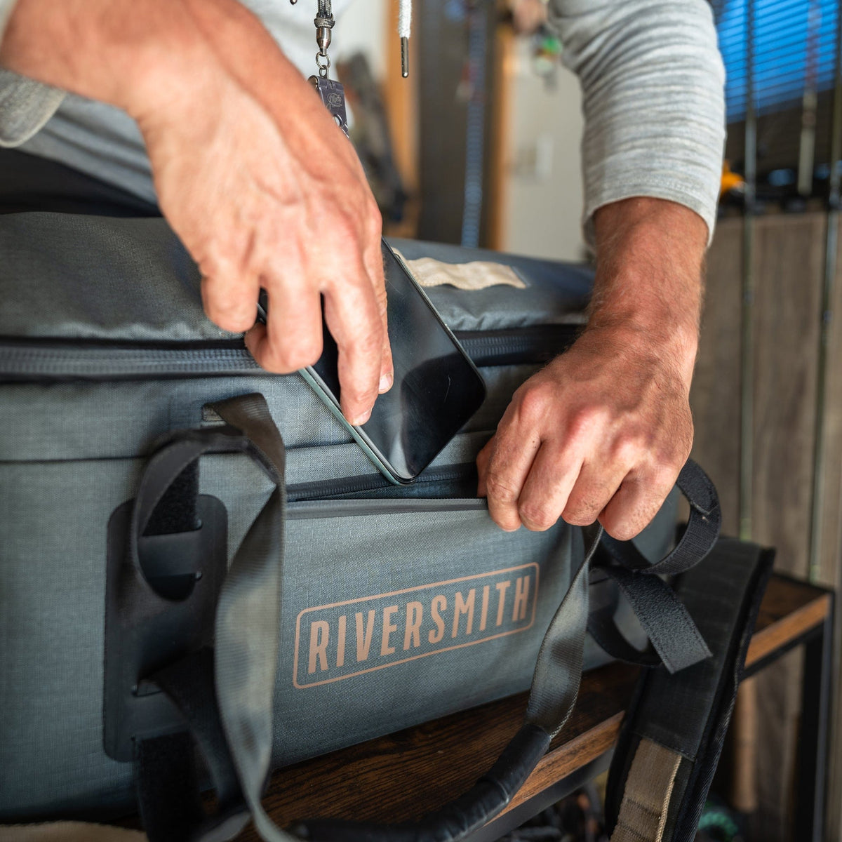 Riversmith waterproof duffel bag in gray being opened, showing durable construction and handles for gear transportation
