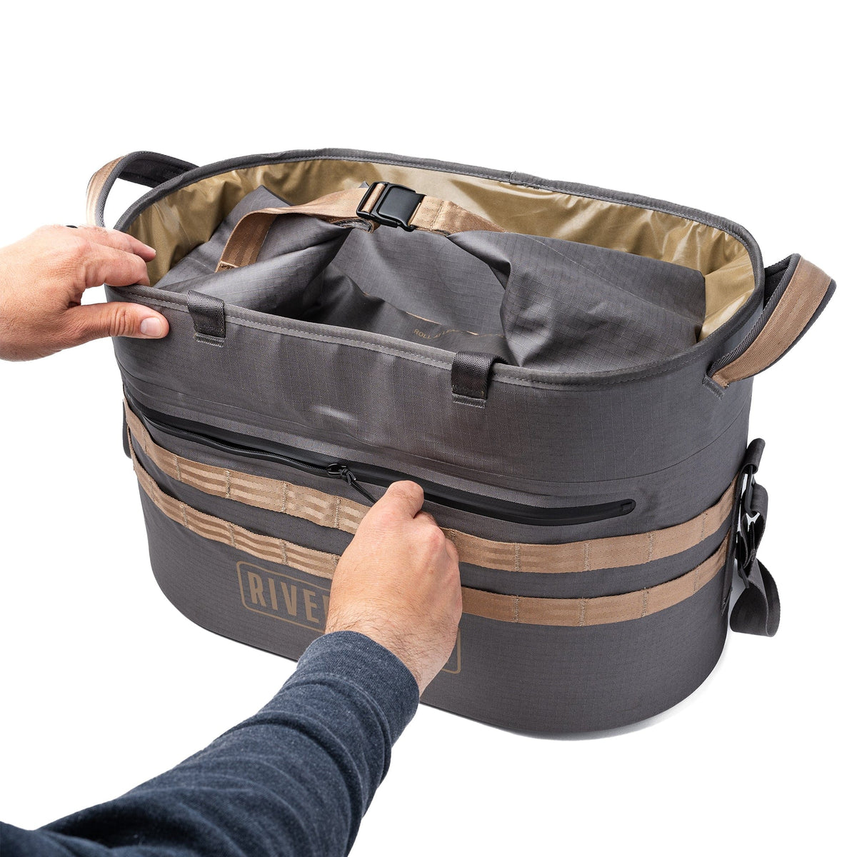 Gray and tan waterproof tote bag open showing interior compartments and handles held by hands
