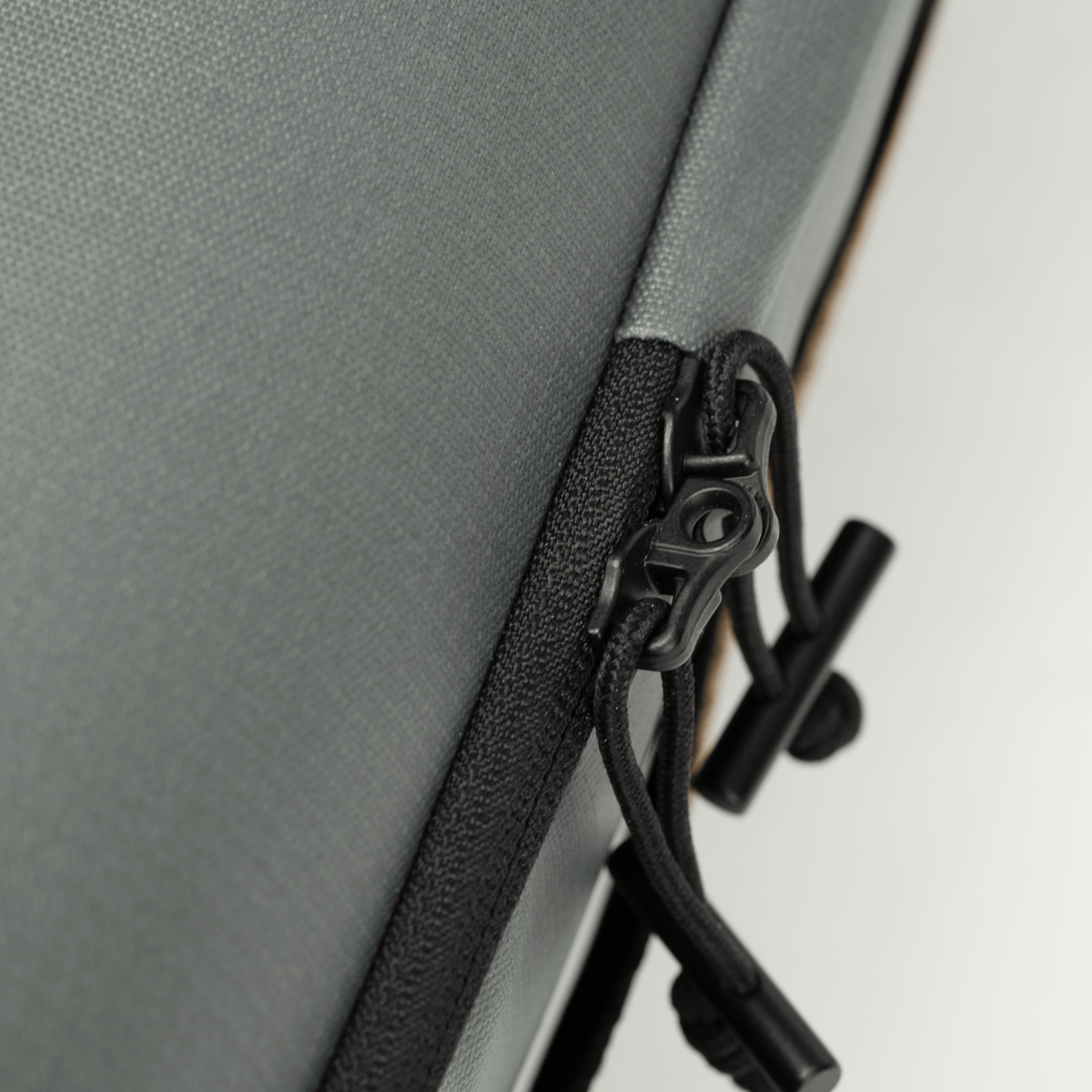 Black zipper and pull tab detail on gray Riversmith Travel Pack fly fishing gear bag