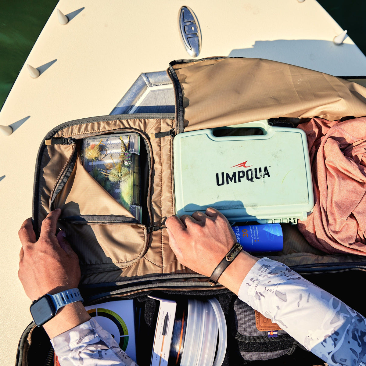 Riversmith Travel Pack fly fishing bag open on boat deck showing Umpqua tackle box and organized compartments with gear