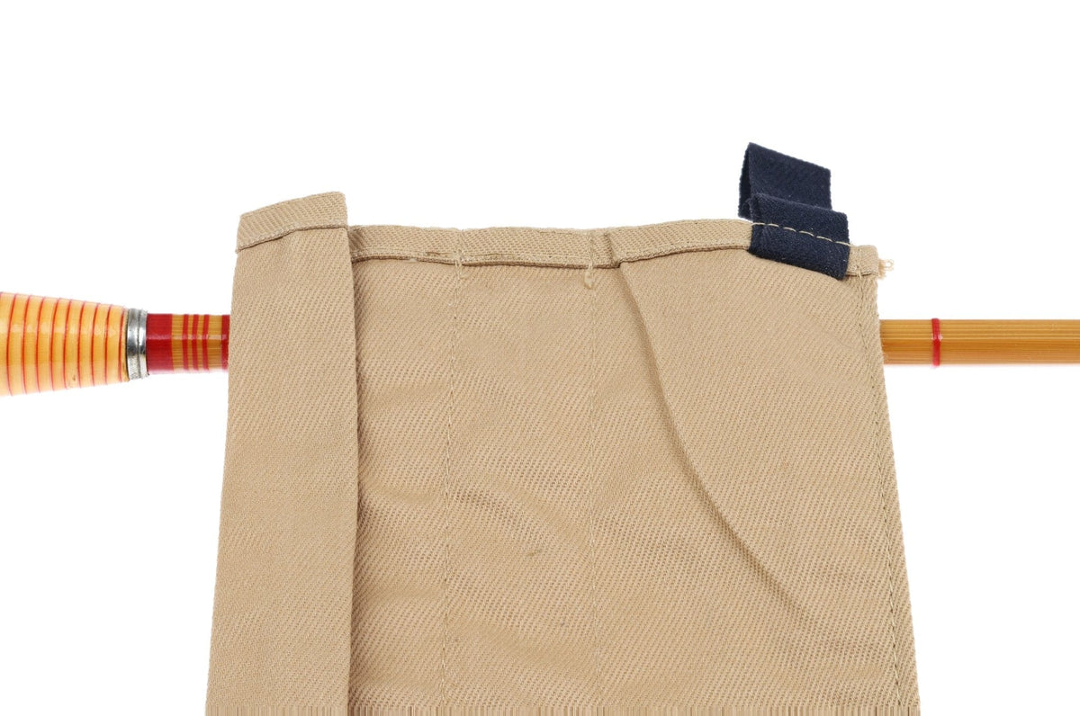 Tan canvas rod sock with navy strap covering bamboo fly rod showing amber section, red thread wraps and ferrule