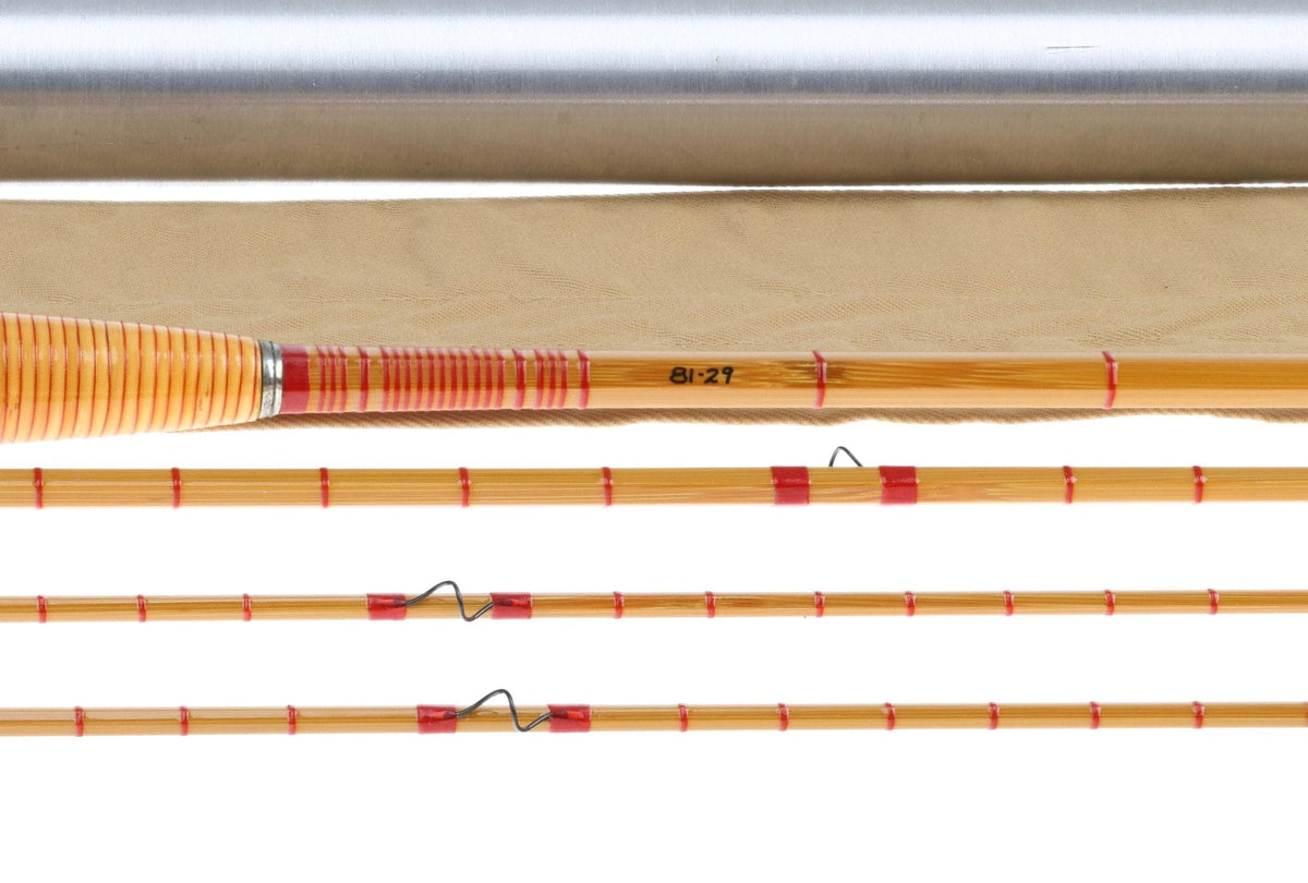 Honey-brown bamboo fly rod sections with red thread wraps, orange striped grip and silver ferrule, vintage style