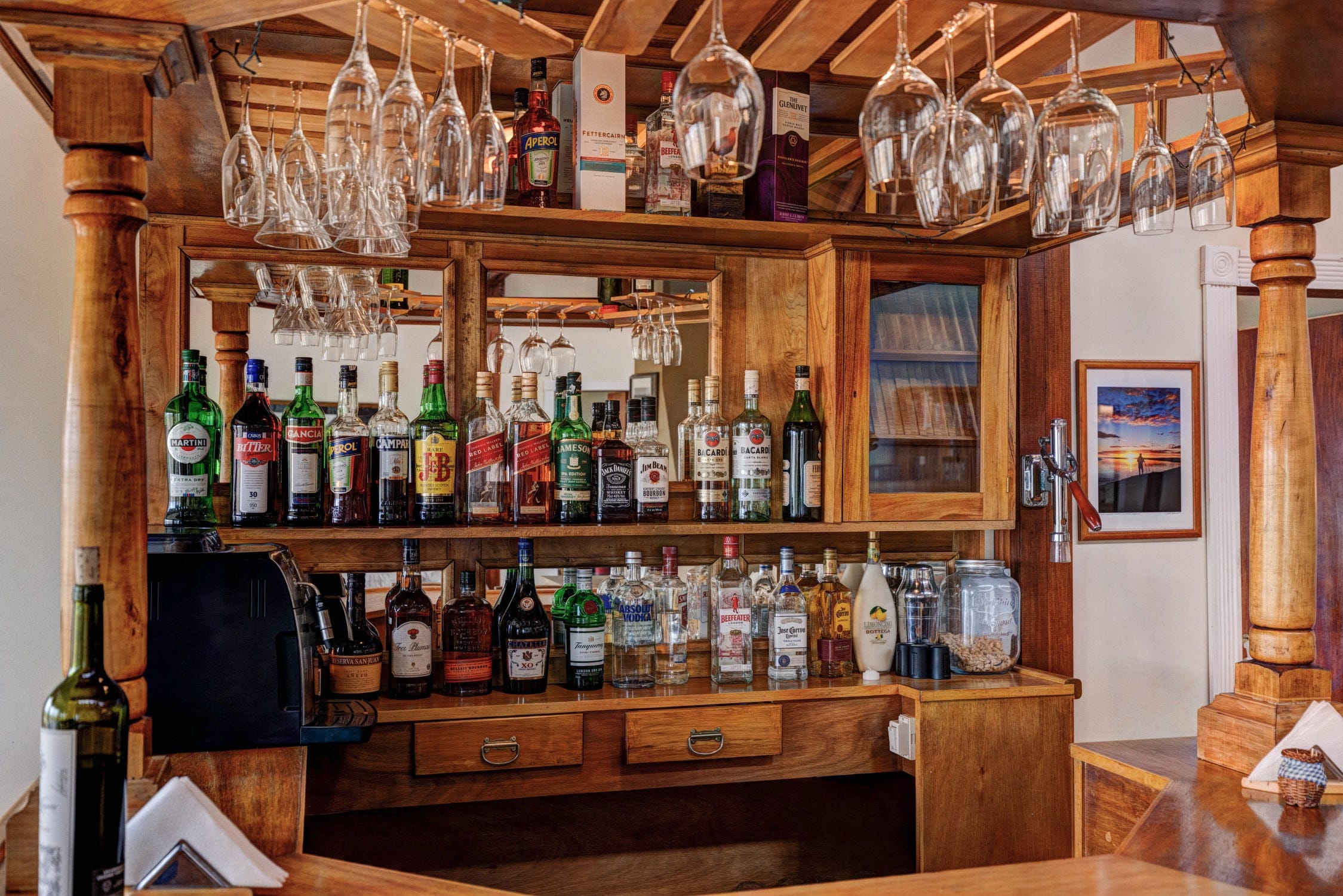 Rustic wooden lodge bar at Maria Behety Lodge with hanging wine glasses and rows of liquor bottles