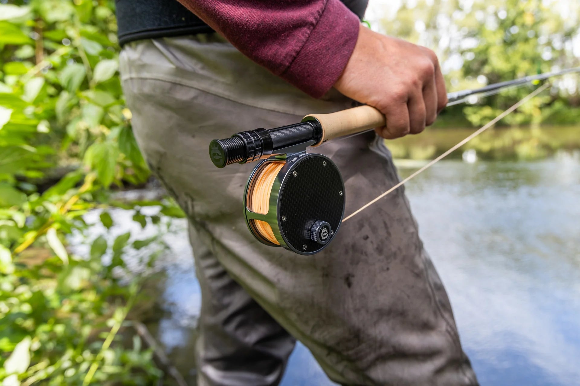 Cortland Retro Click fly reel with black carbon-fiber face, olive metallic spool and orange line on cork handle