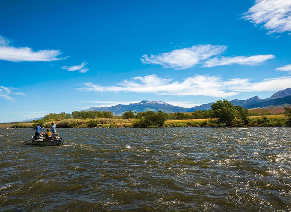 Trident Madison Double R raft gliding across a scenic mountain river with clear blue skies