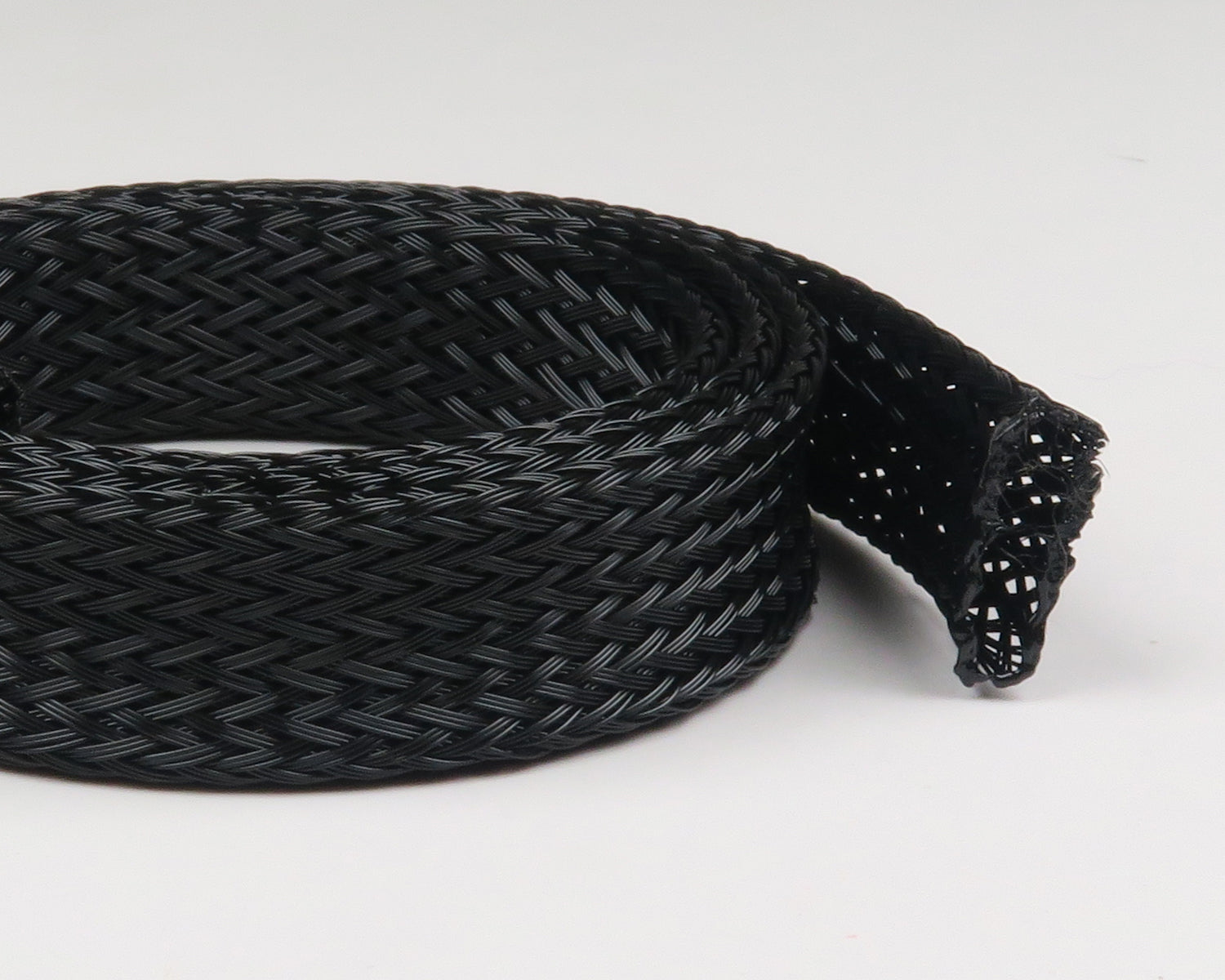 Black braided synthetic body tubing coil with open woven mesh end for fly tying