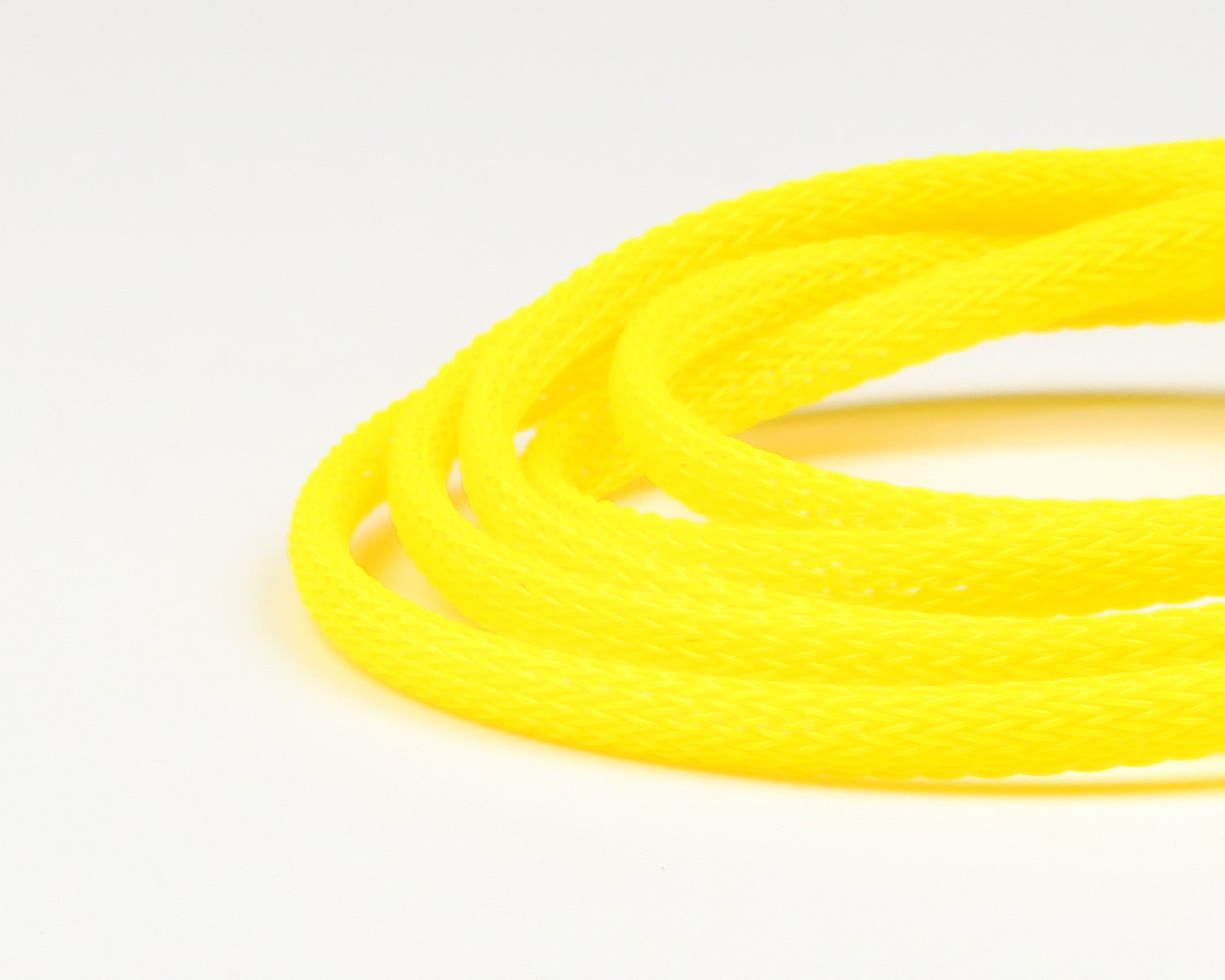 Fluorescent yellow braided synthetic body tubing coiled, glossy nylon-like material for fly tying