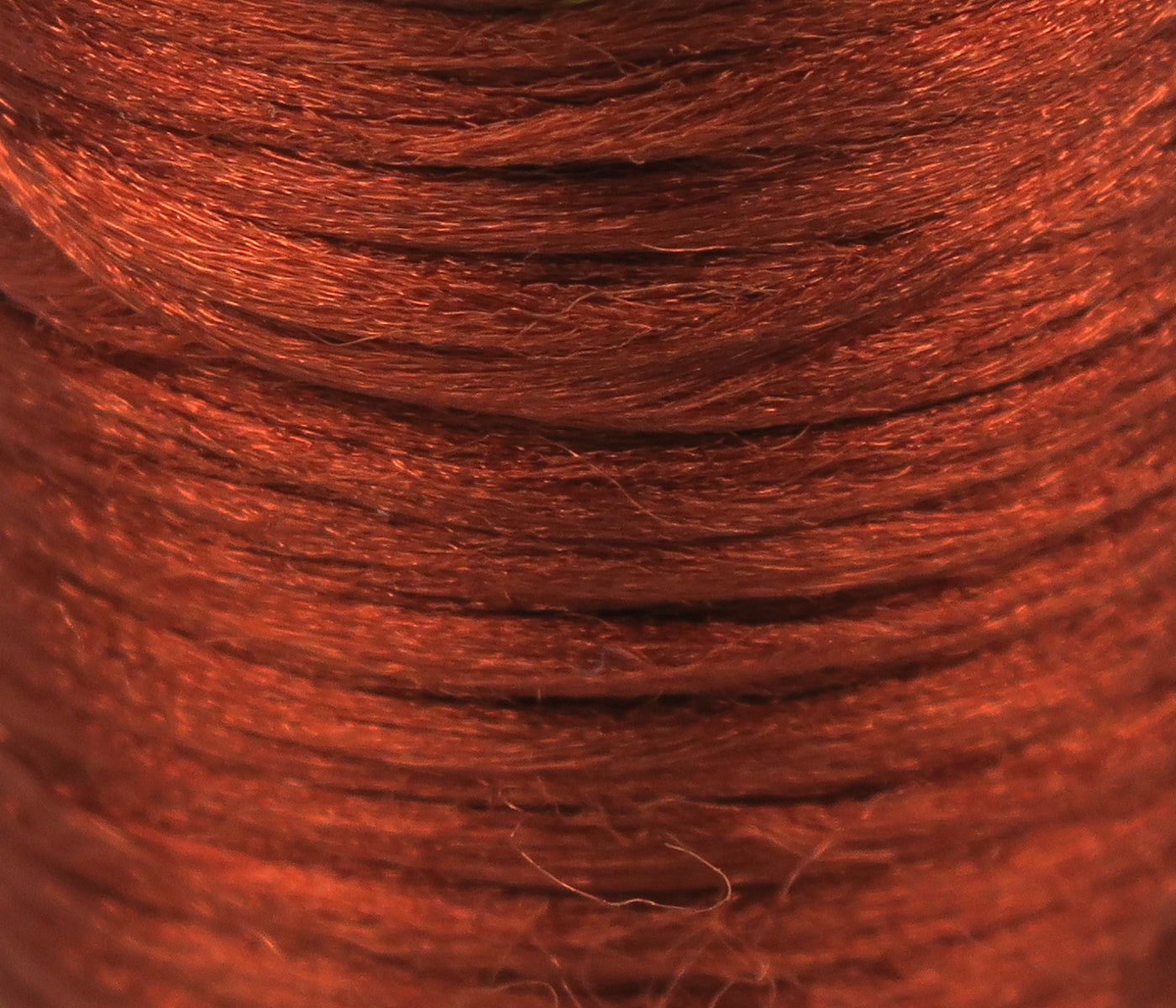 Copper-red Antron yarn close-up showing fine, slightly fuzzy synthetic strands with subtle sheen for fly tying