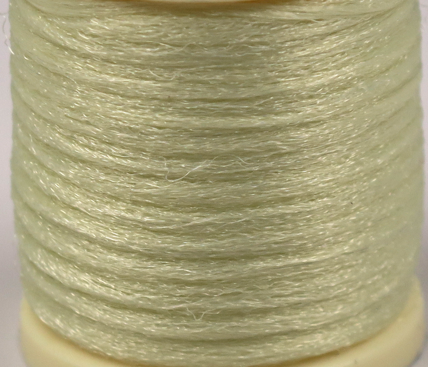 Hareline Antron yarn spool in pale chartreuse green with shiny synthetic fibers wound for fly tying